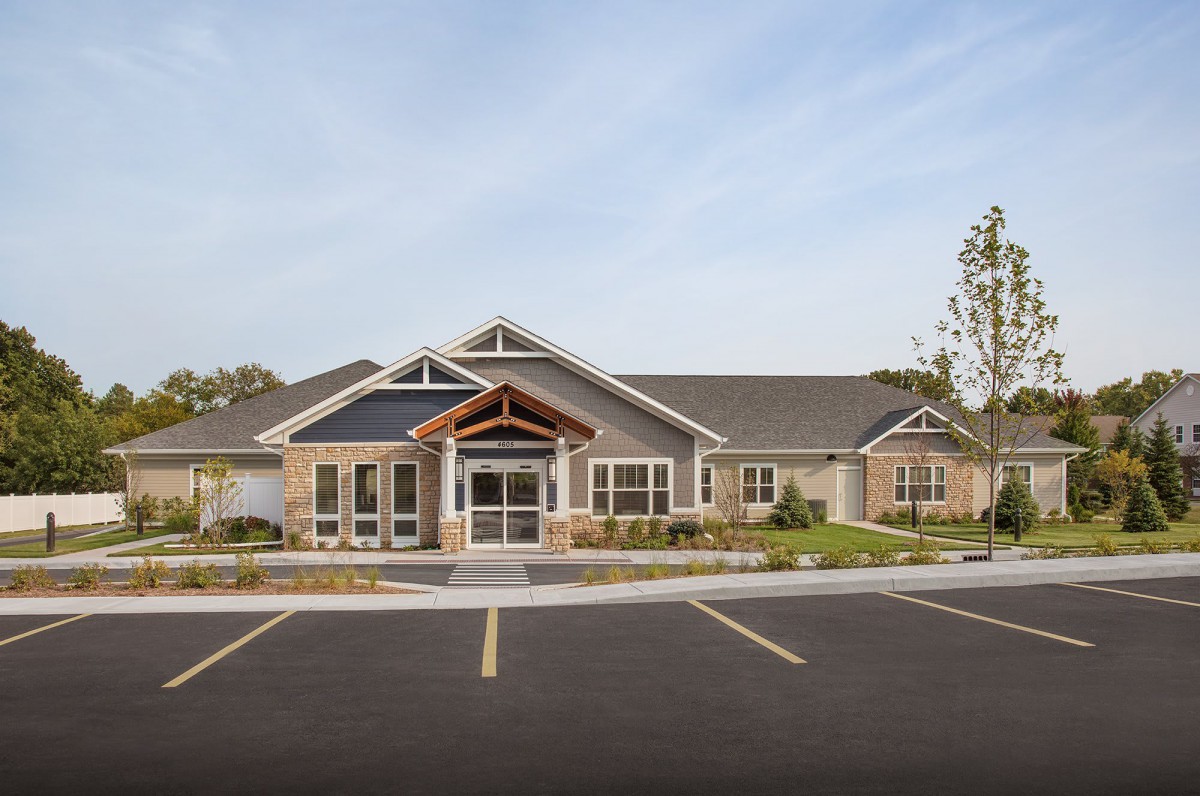 A suburban residential building with a parking lot in front, captured during the daytime.