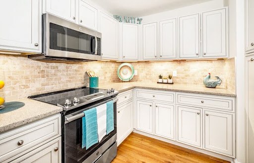 A bright and modern kitchen featuring white cabinetry, stainless steel appliances, and stylish blue accents.