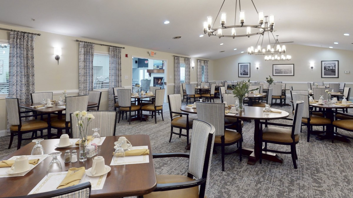 An elegant dining room with neatly arranged tables and chairs, featuring a chandelier and tasteful decor.