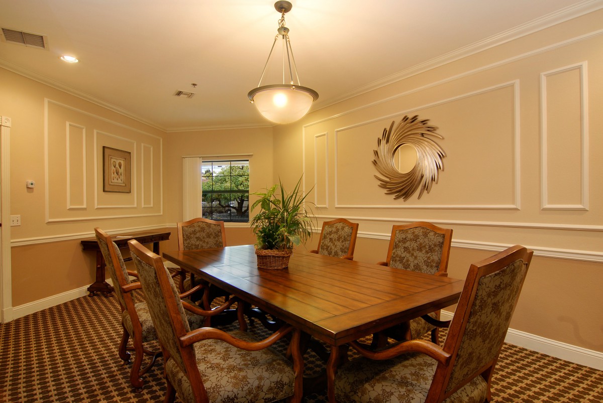 A well-decorated conference room with a large wooden table, upholstered chairs, and elegant lighting.