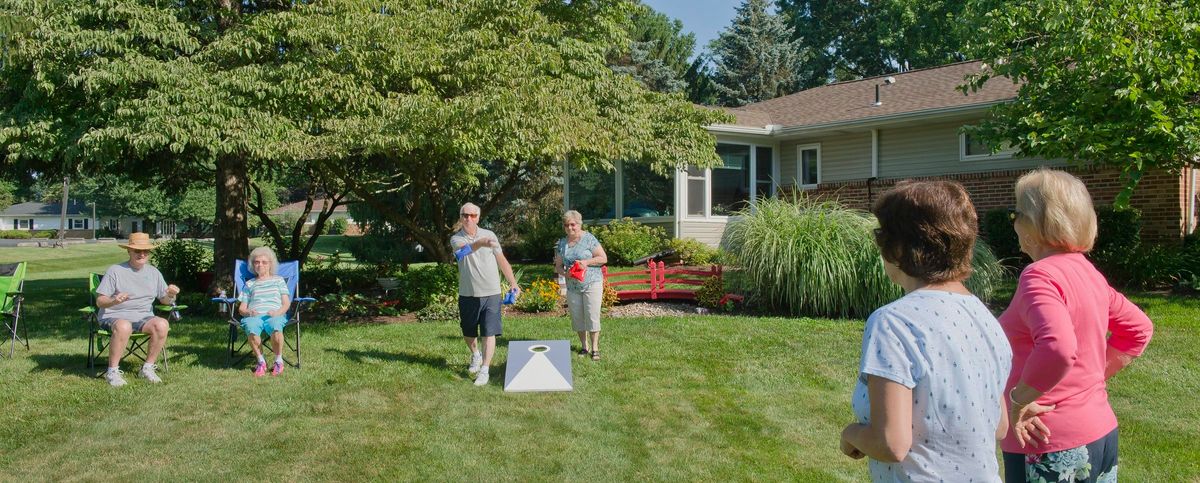 Two people playing a lawn game in a backyard on a sunny day.