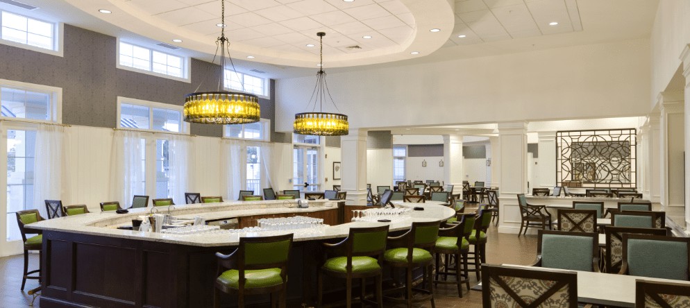 A modern bar with green chairs and stylish lighting.