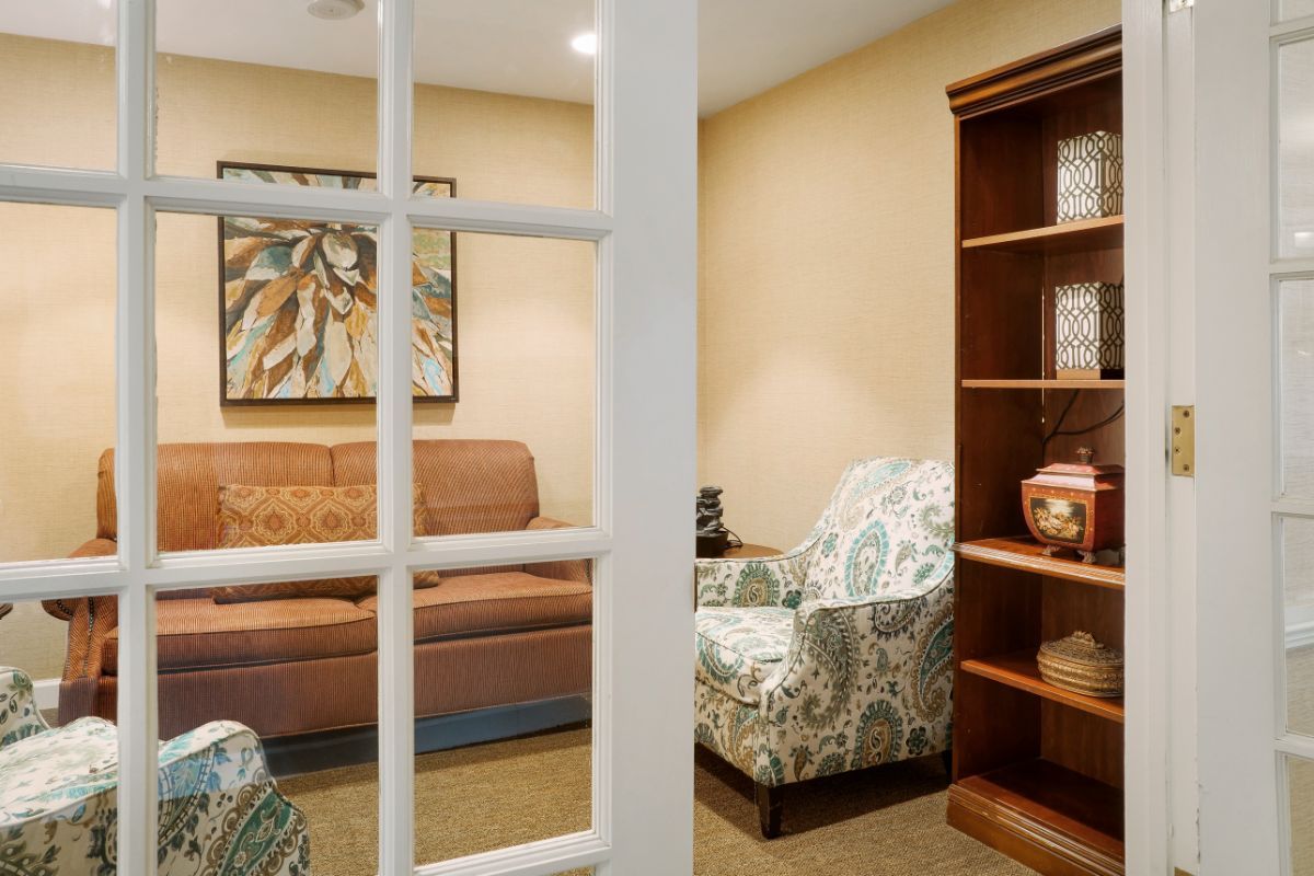 A cozy living room with a sofa, armchair, and a wooden bookshelf.