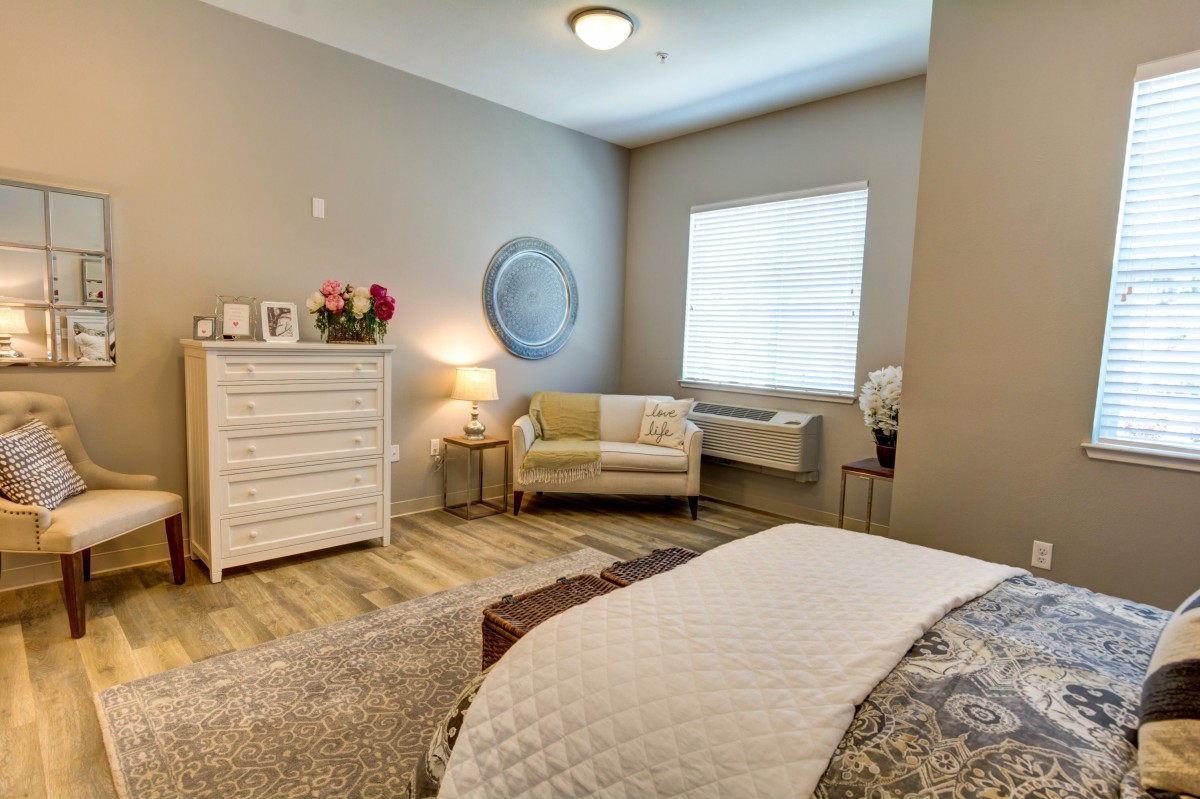 A cozy and modern bedroom with white furniture and soft lighting.
