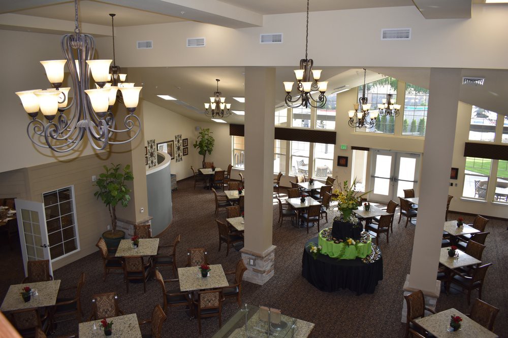 A spacious dining area with elegant chandeliers, abundant natural light, and neatly arranged tables and chairs.