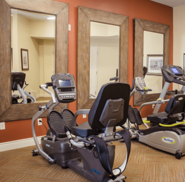 A small gym room with exercise equipment and large mirrors on the walls.