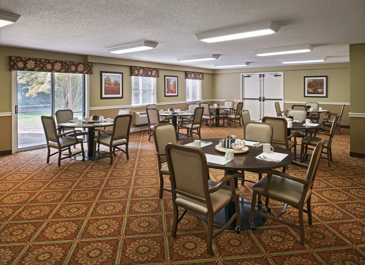 An elegant dining room with multiple tables and chairs arranged on a patterned carpet.