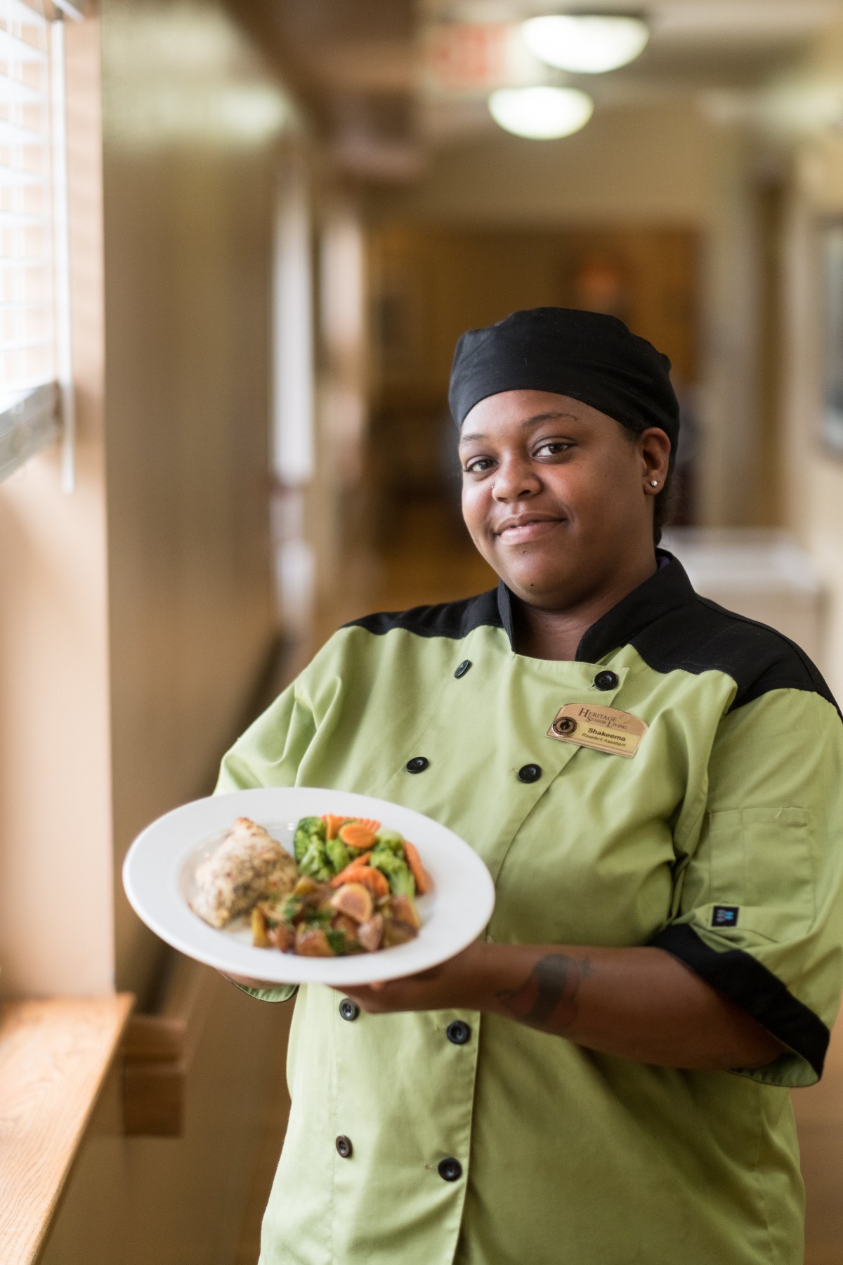 A chef presenting a plated dish in a professional kitchen.