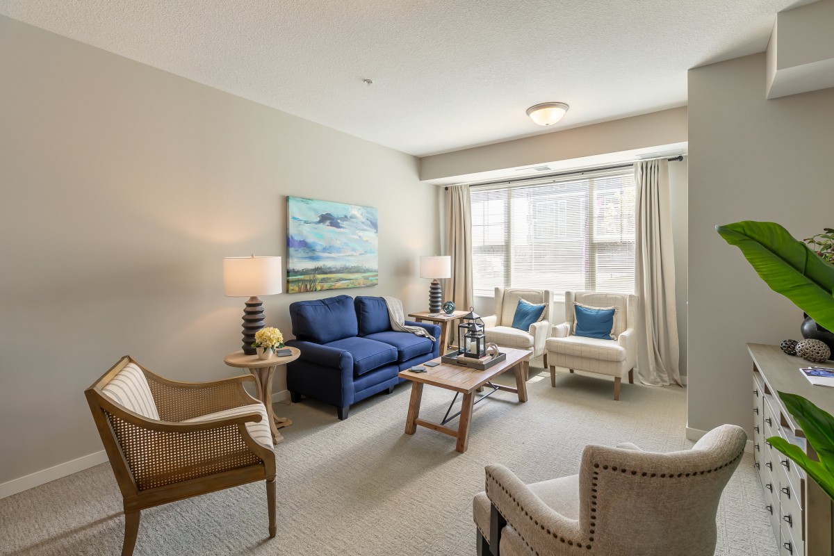 A cozy and well-lit living room with a blue sofa, armchairs, and a coffee table.