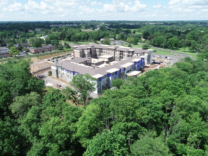 Aerial view of a building under construction surrounded by lush greenery.