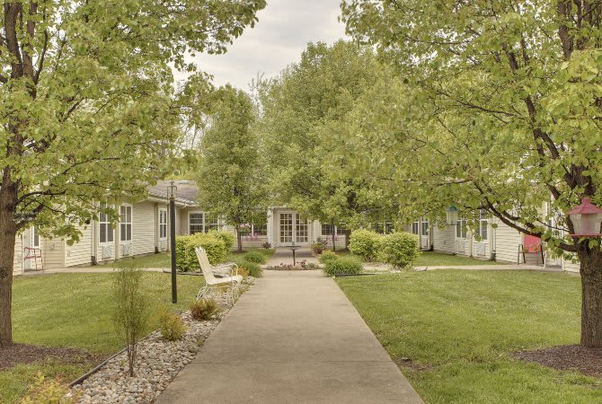 A serene outdoor pathway surrounded by lush greenery and buildings.