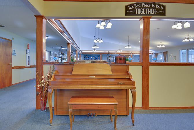 A cozy music room featuring a piano and bench, adorned with a motivational sign.