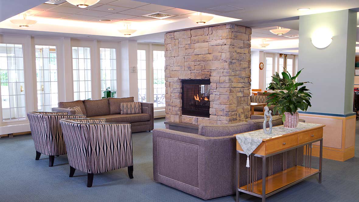 A cozy living room with a central stone fireplace and comfortable seating.