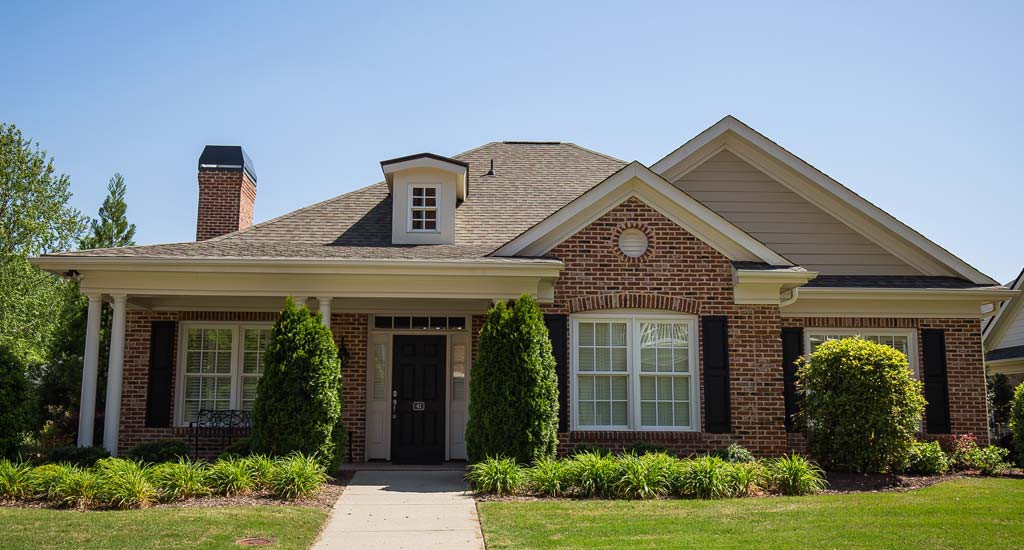 A charming suburban brick house with a manicured front yard.