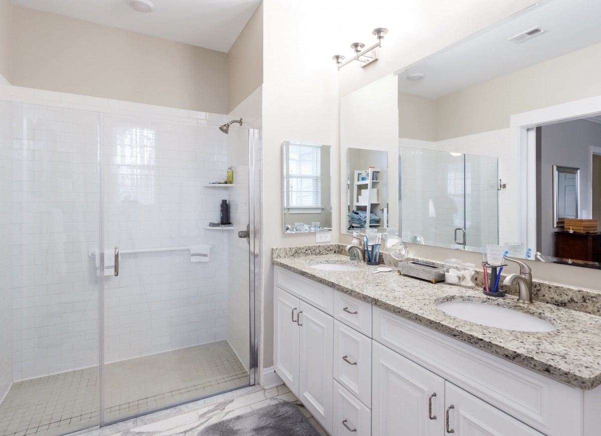 A modern bathroom featuring a glass-enclosed shower and a double-sink vanity.