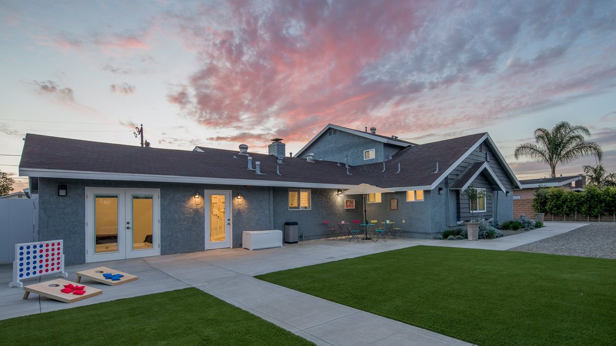 A suburban house with a spacious yard at twilight, under a colorful sky.