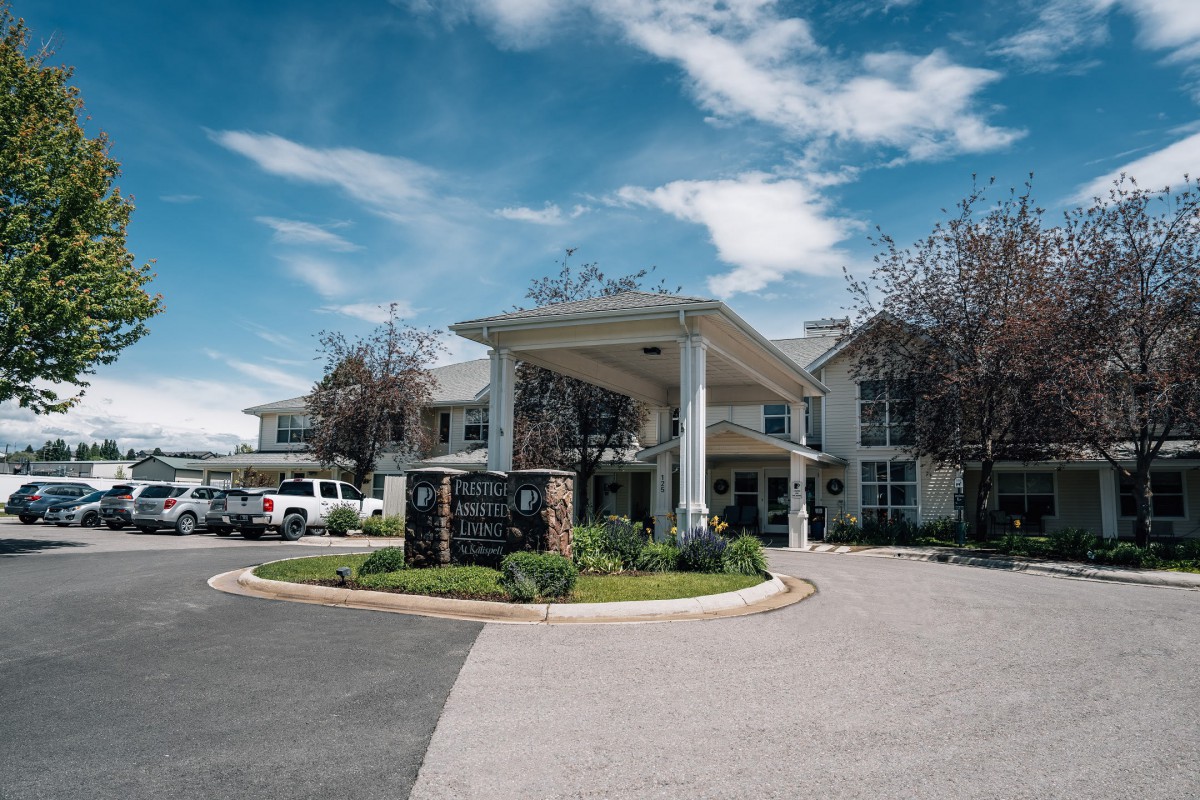 A two-story building with a covered entrance, surrounded by landscaped greenery under a partly cloudy sky.
