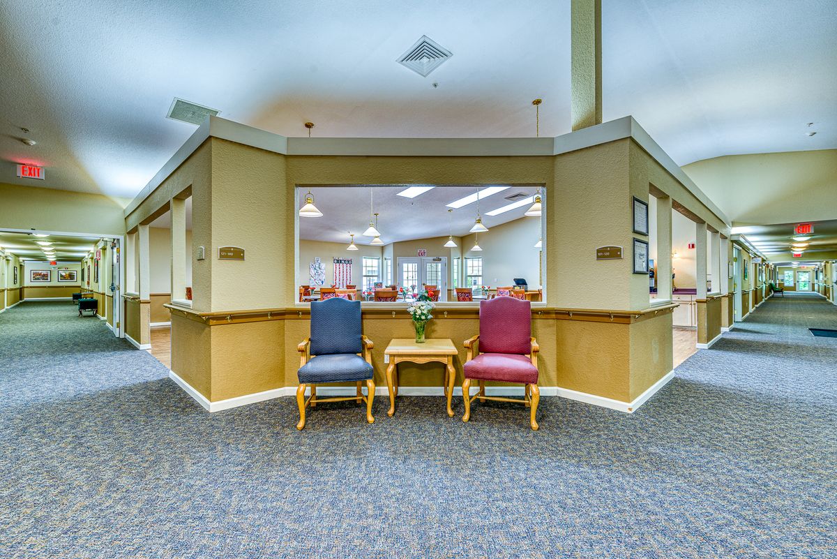 A view of a waiting area with two chairs and a small table, leading to a reception desk.