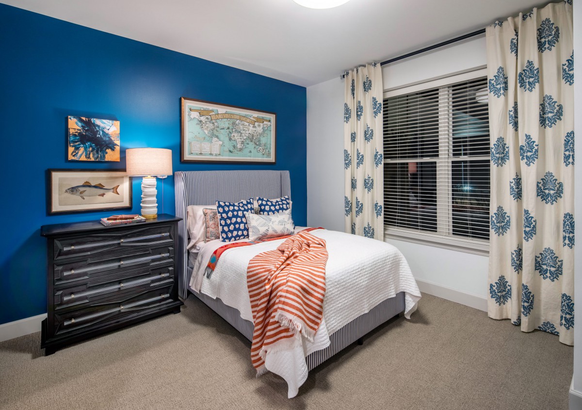 A modern bedroom with a blue accent wall and stylish decor.
