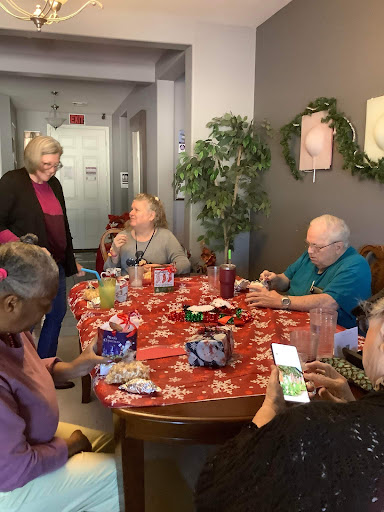 A lively gathering of seniors enjoying drinks and conversation around a festive table.