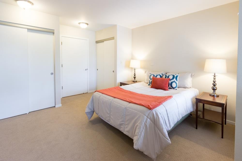 A modern bedroom with a cozy bed, adorned with colorful pillows and a bright throw blanket.