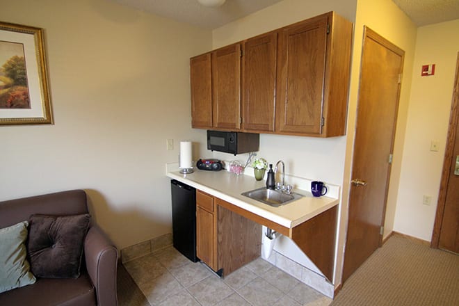 A small kitchenette with wooden cabinets, a sink, and a mini fridge.