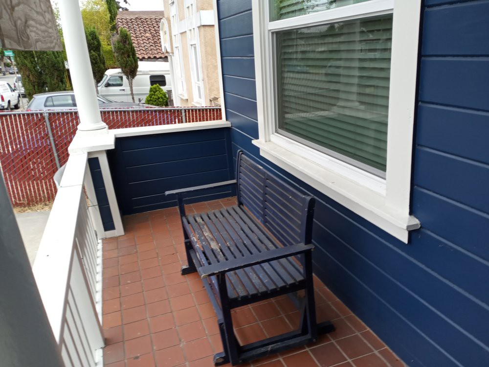 A small porch with a blue wall and a wooden bench.