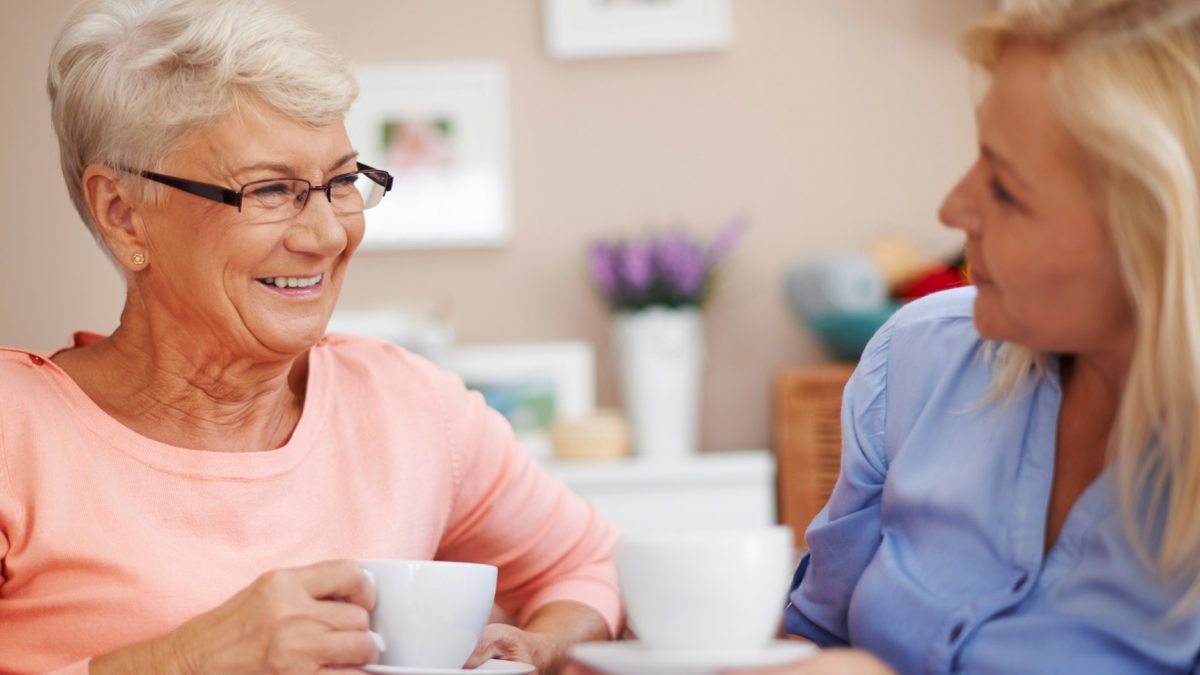 Two seniors enjoying coffee and conversation indoors.