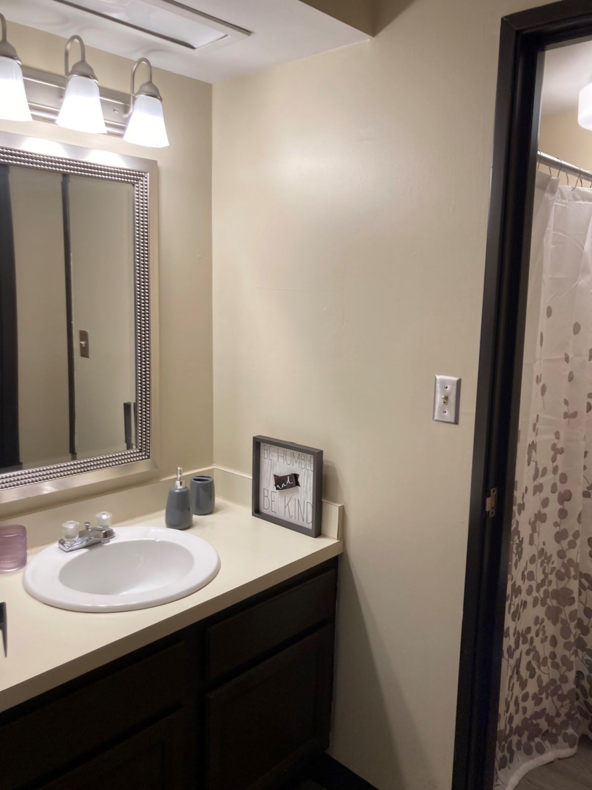 A clean and modern bathroom with a sink, mirror, and shower.