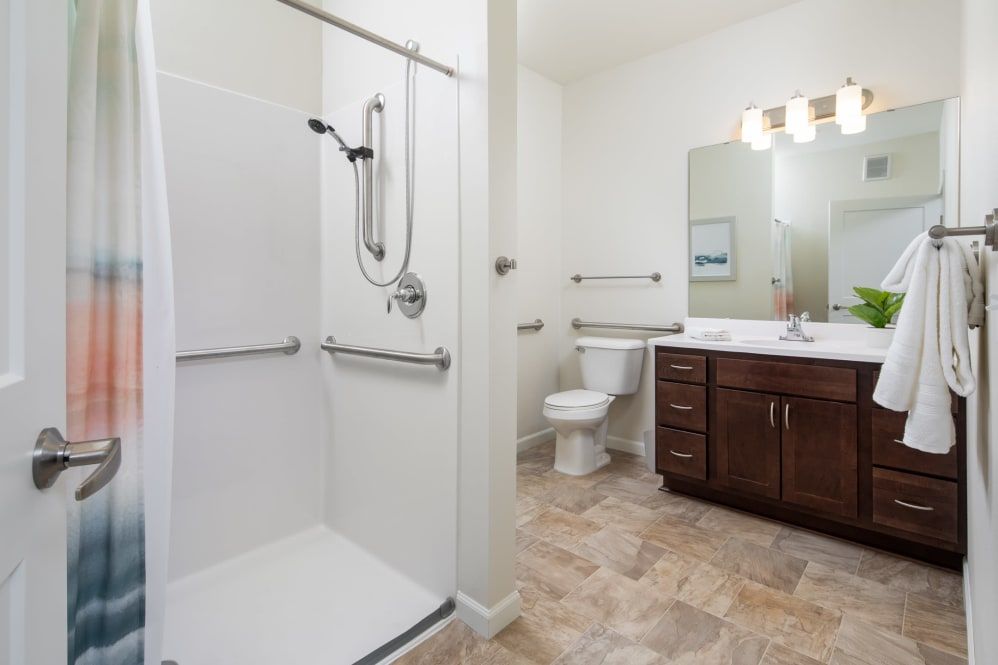 A modern and accessible bathroom with a shower, toilet, and sink.
