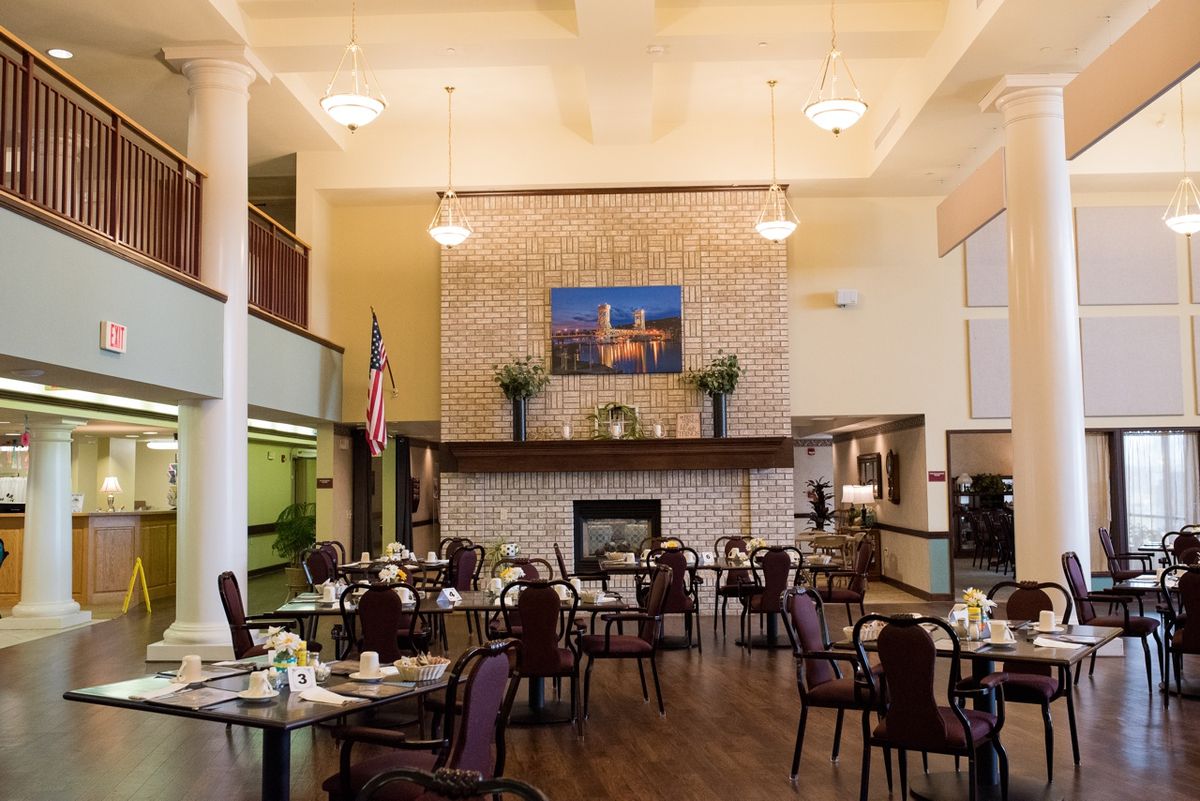 A spacious dining area with neatly arranged tables and chairs, featuring a central fireplace and elegant decor.