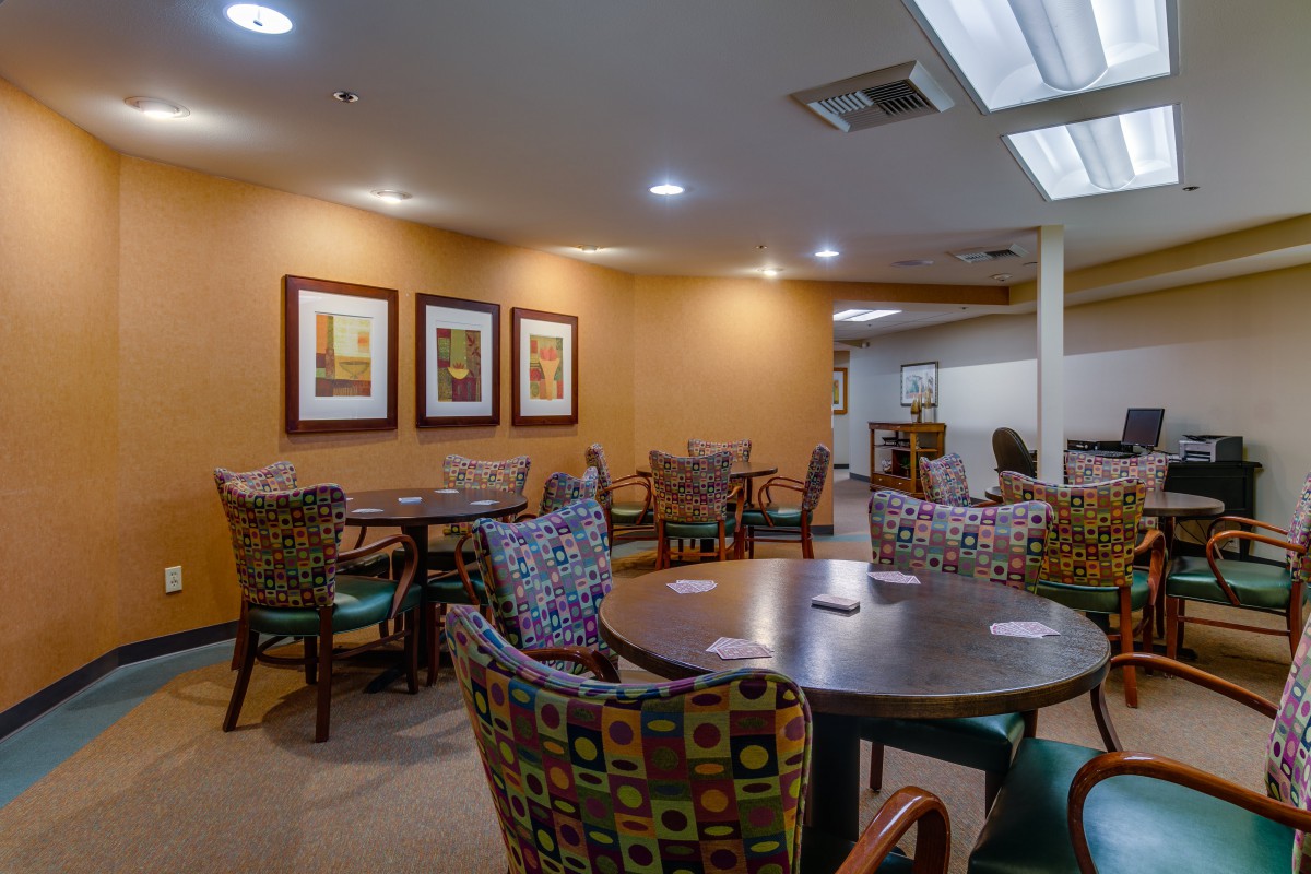 A cozy dining area with colorful chairs and artwork on the walls.