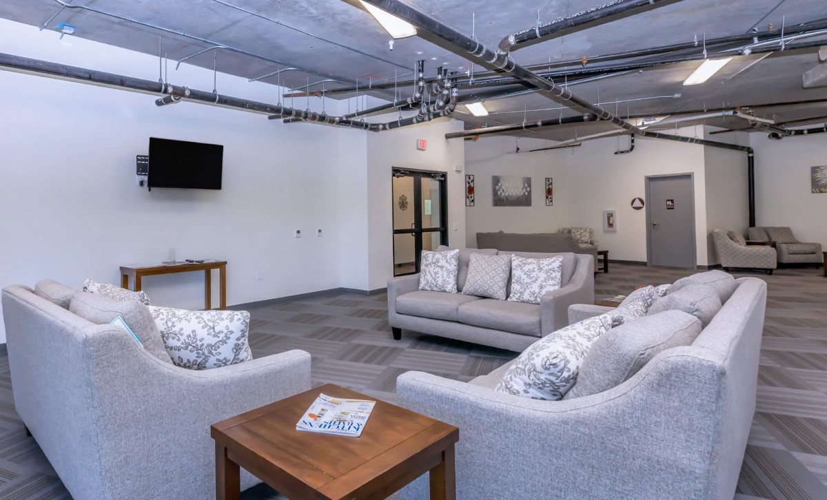 A modern living room with industrial elements featuring gray sofas, a coffee table, and a wall-mounted TV.