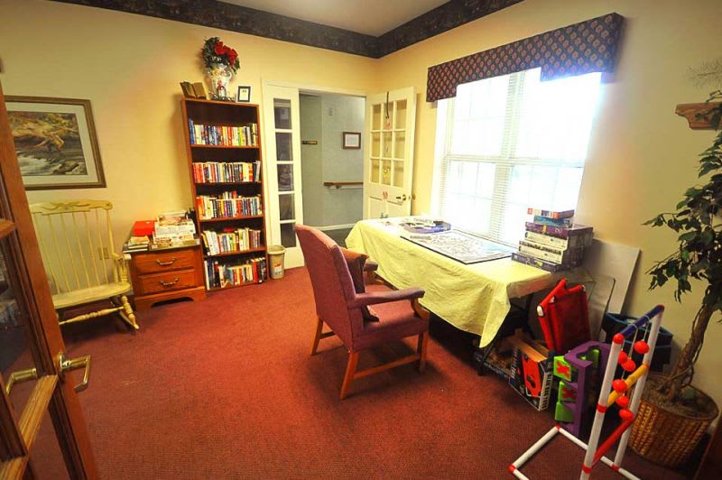A cozy living room with a desk, chair, and bookshelf filled with books.