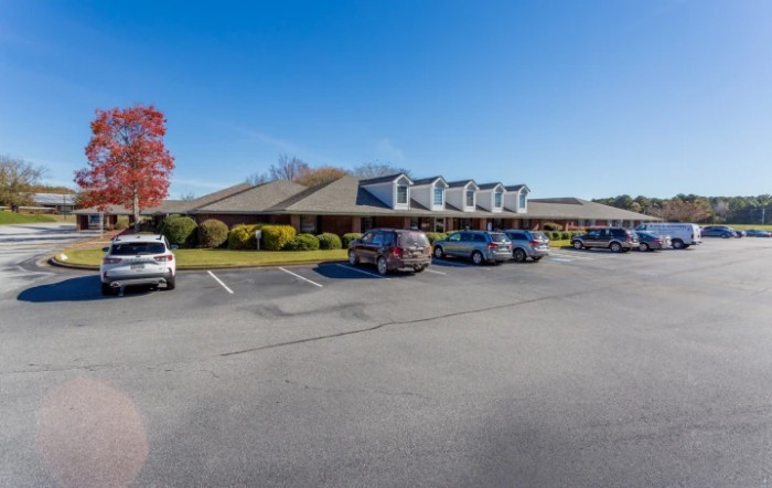 A parking lot in front of a large building on a clear day.