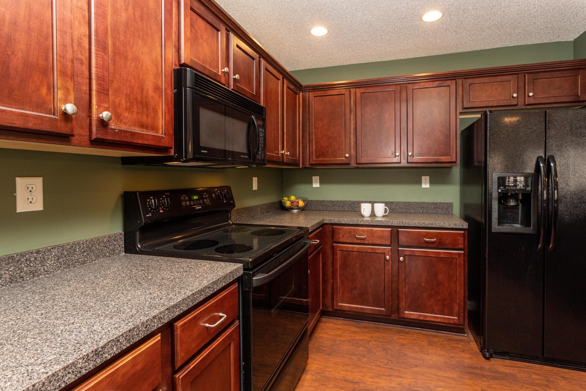 A modern kitchen with wooden cabinets and essential appliances.