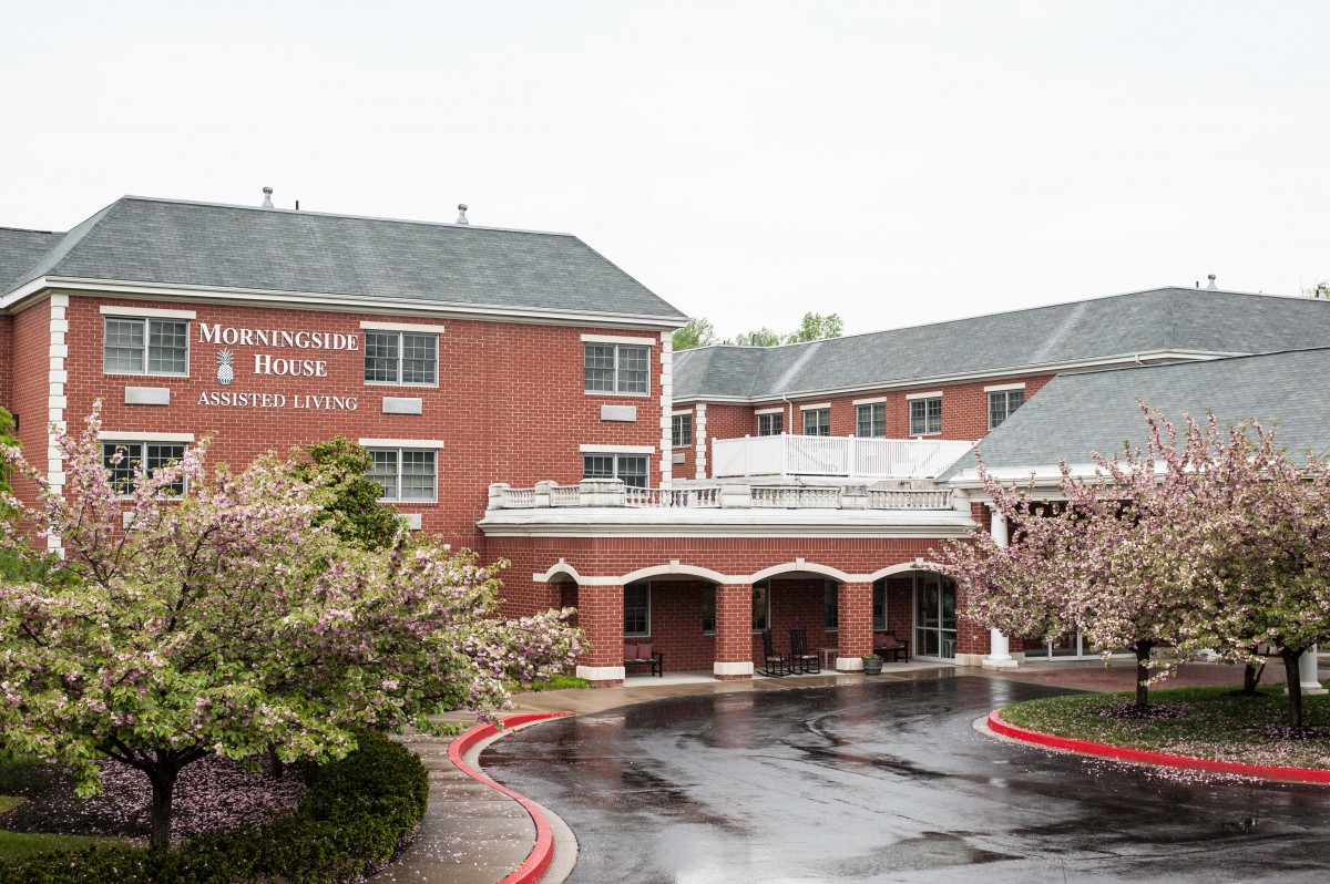 A brick hotel building with a welcoming entrance and surrounding trees.