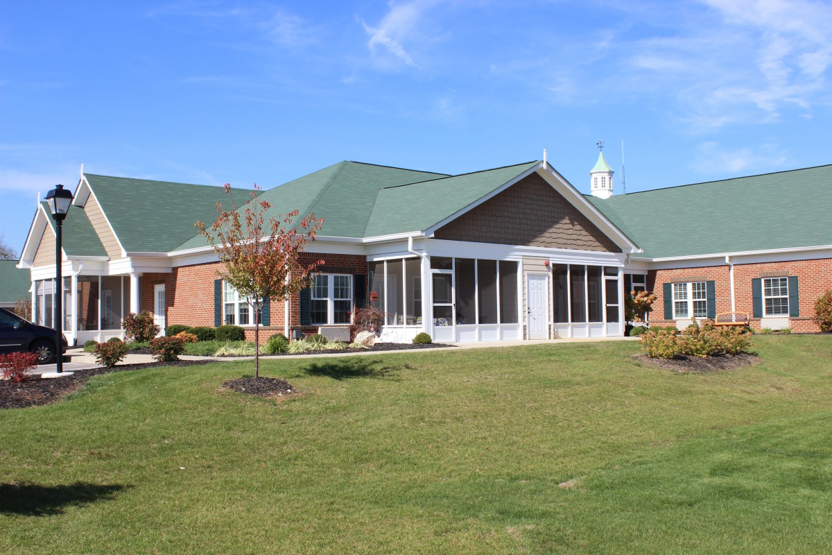 A residential building with a green roof and well-maintained lawn under a clear blue sky.