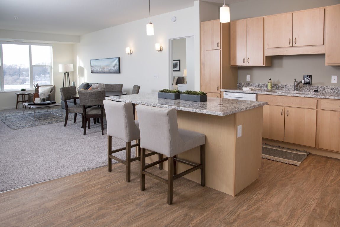 A modern open-concept kitchen and dining area with wooden flooring and stylish bar stools at the countertop.
