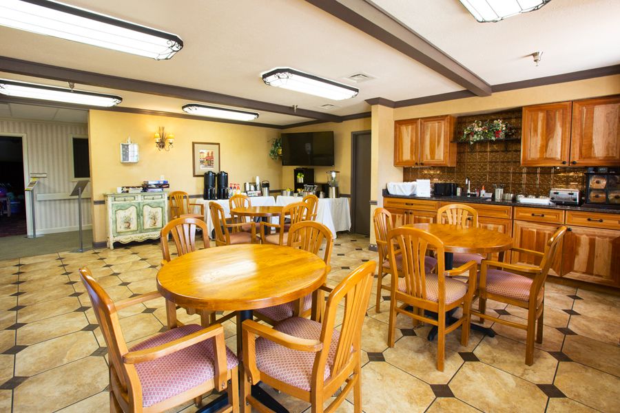 A cozy dining area with wooden tables and chairs, featuring a kitchenette equipped with various amenities.