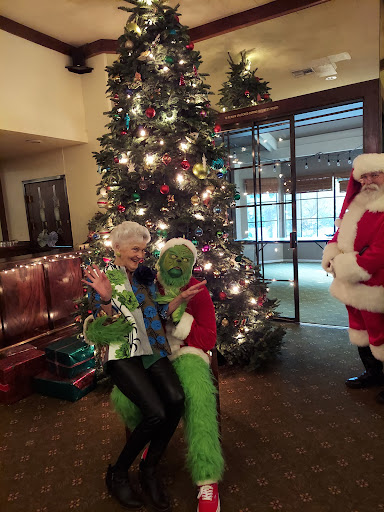 A festive holiday gathering featuring a cheerful Christmas tree, Santa Claus, and a playful Grinch.