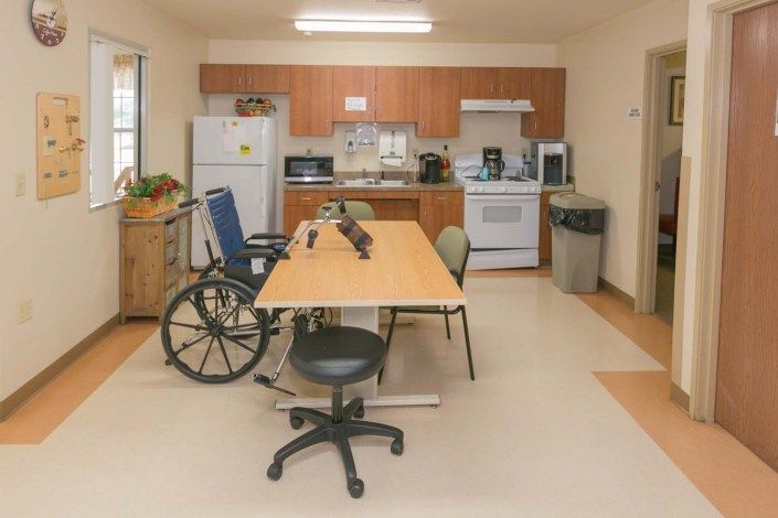 A kitchen setup with a table, chairs, and a wheelchair indicating an accessible space.