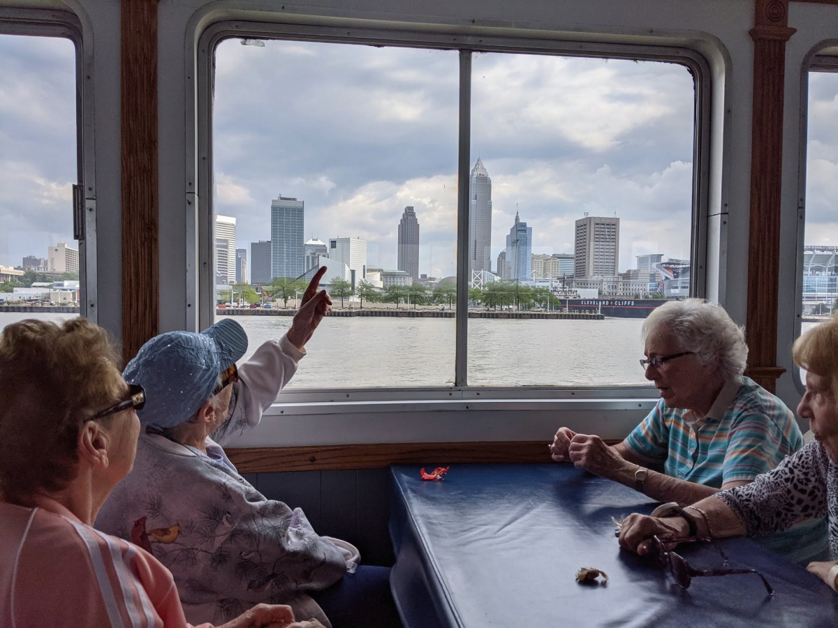 A group of seniors enjoy a scenic city skyline view from a boat window.