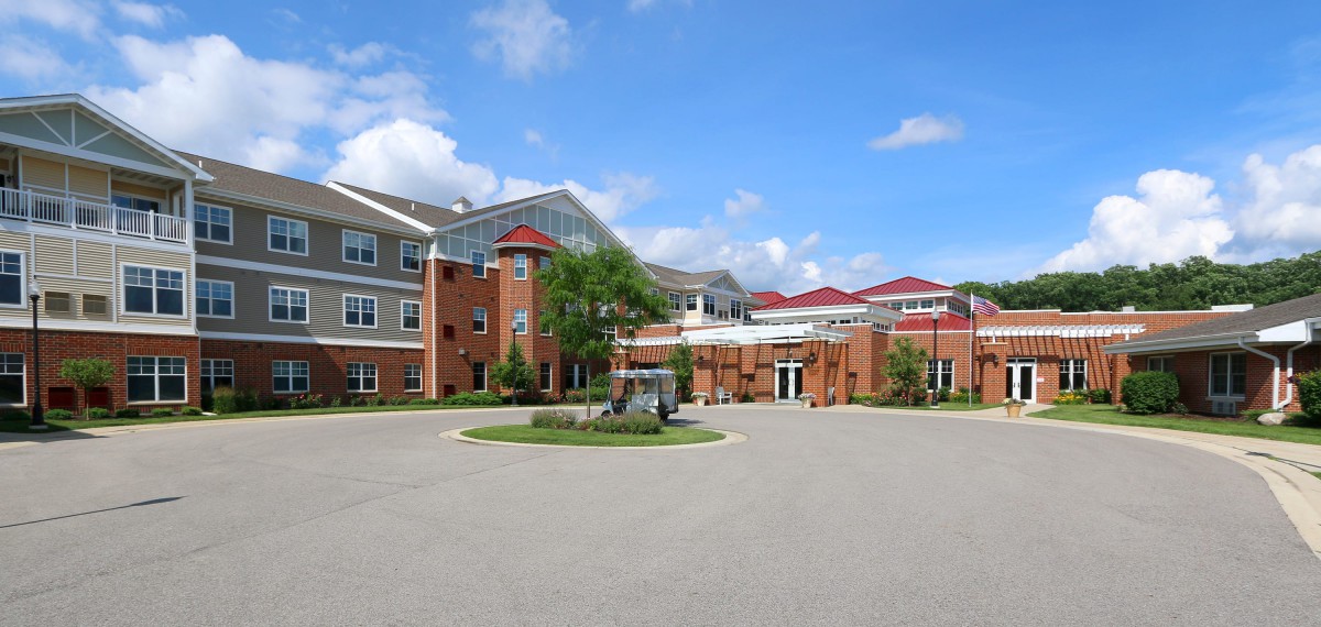 A modern residential building with red brick facade and well-kept landscaping.
