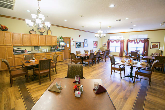A cozy dining room with wooden floors and neatly arranged tables and chairs.