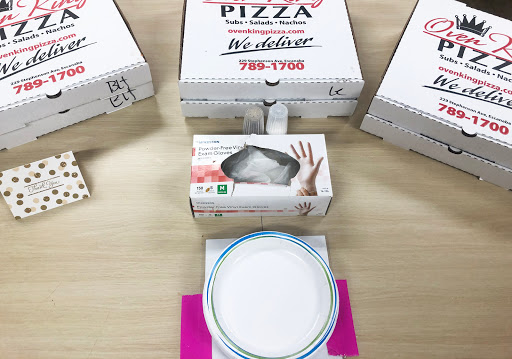 A collection of pizza boxes alongside a takeout container and a plate, ready for a meal.