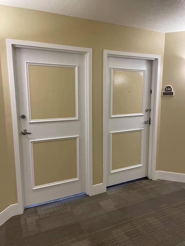 A hallway with two closed doors featuring beige and white paneling.