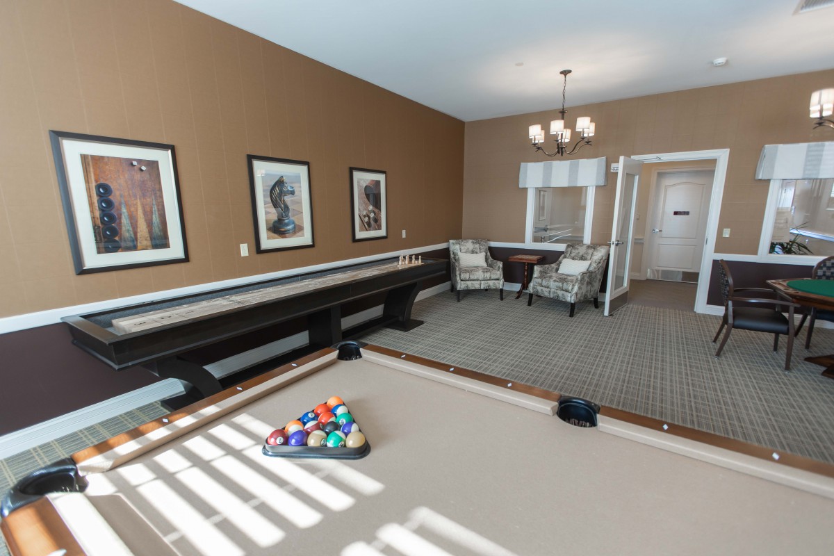 A well-lit billiards room featuring a pool table and comfortable seating.