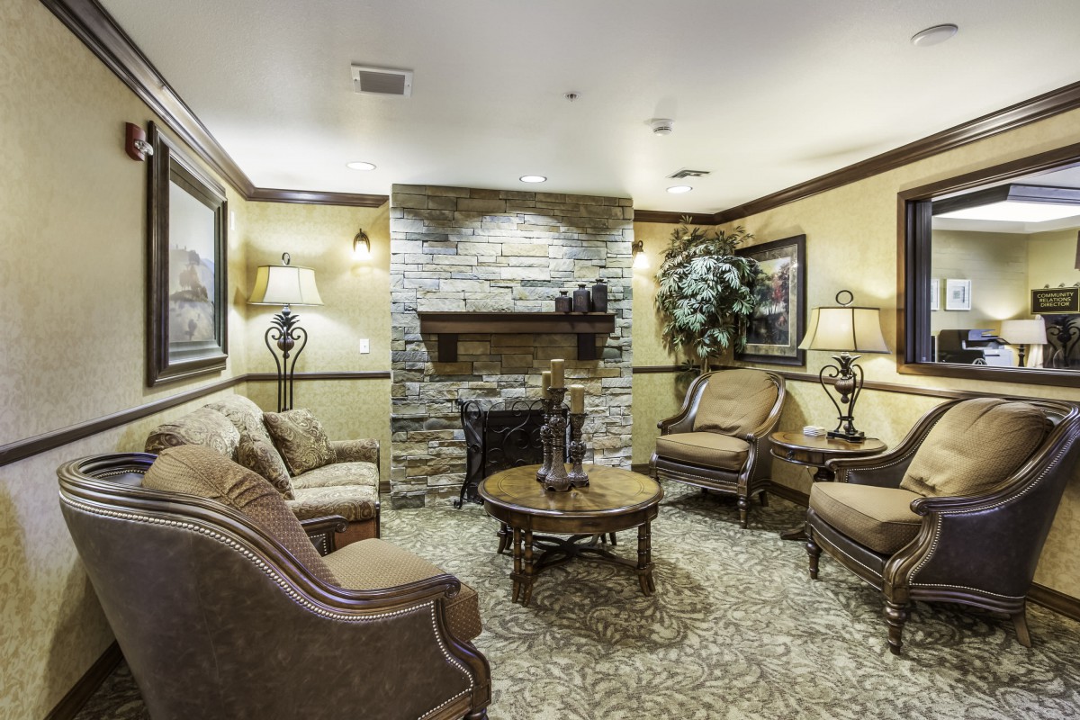 A cozy living room with a stone fireplace, traditional furniture, and warm lighting.