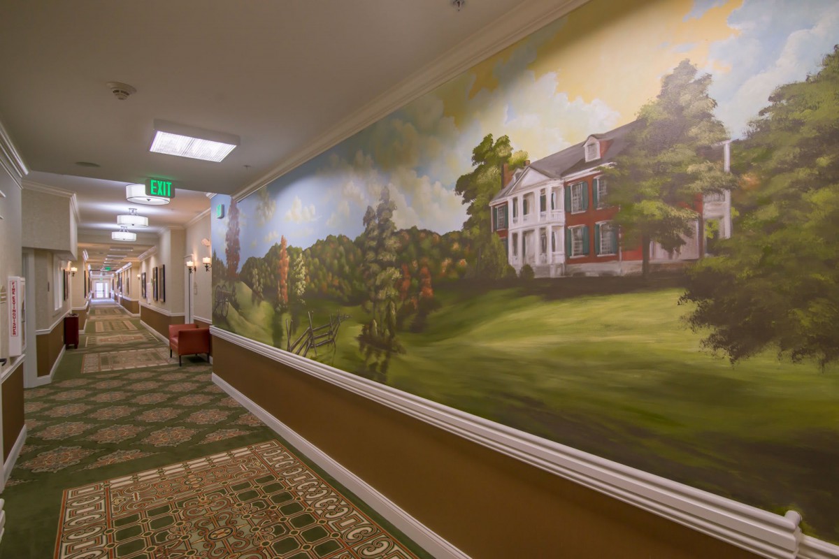 A hallway featuring a large mural of a scenic landscape with a building in the background.